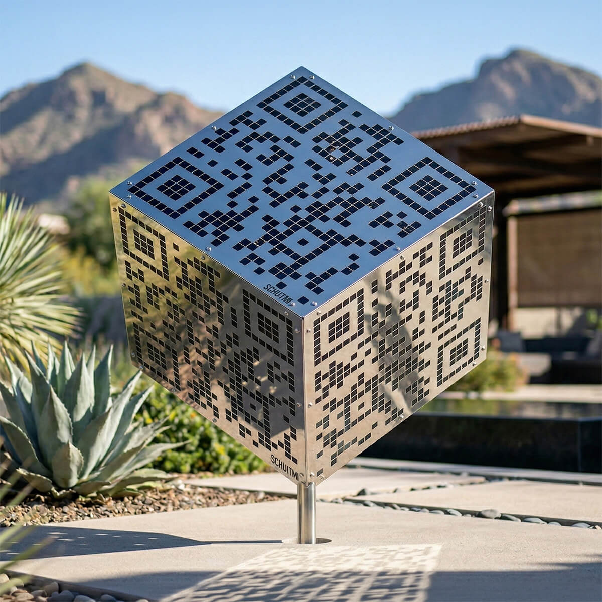 A reflective stainless steel sculptural monolith with a functional QR code pattern built into its surface.