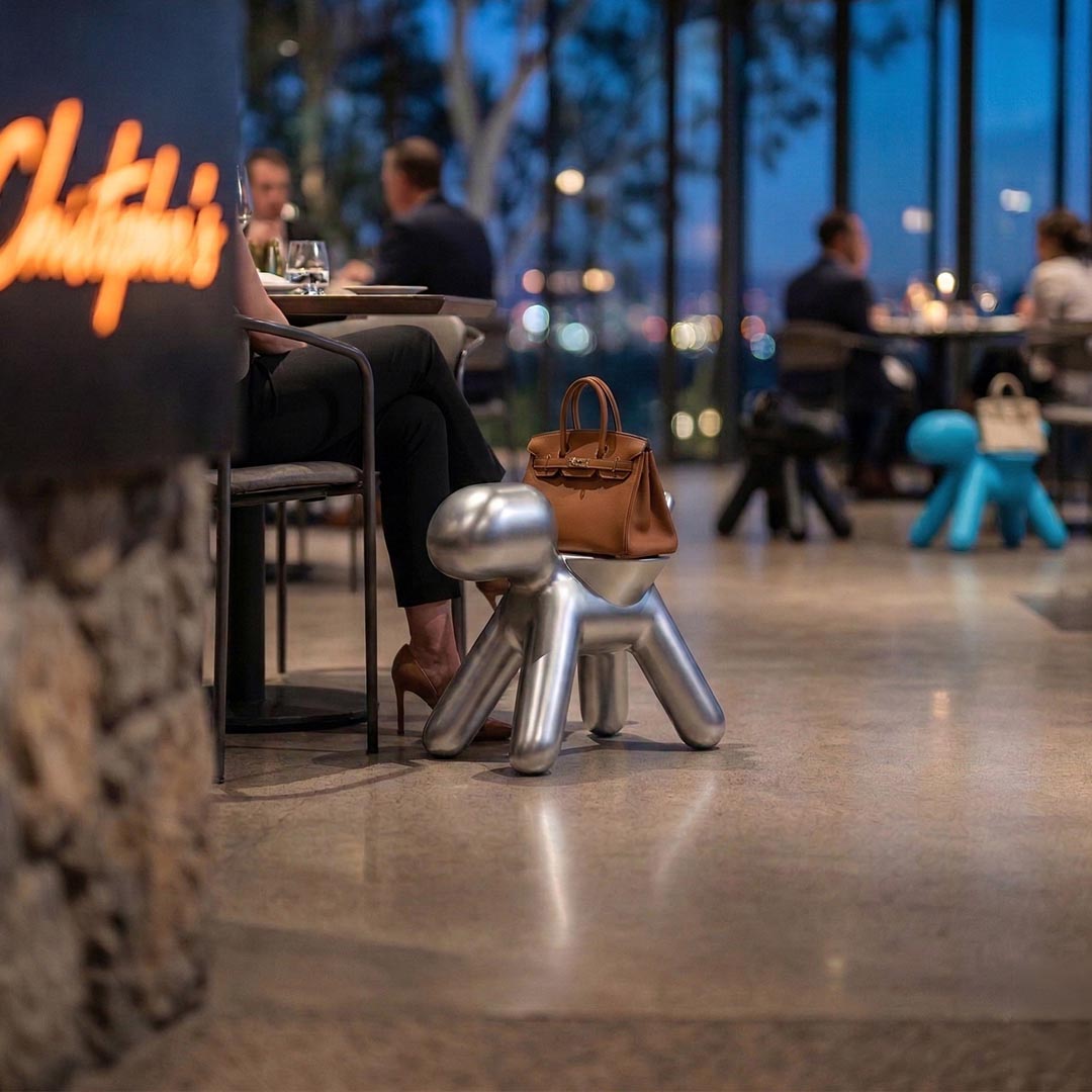 The Purse Pooch, a 3D-printed dog-shaped handbag holder, styled at a dining table alongside other sculptural accent pieces.